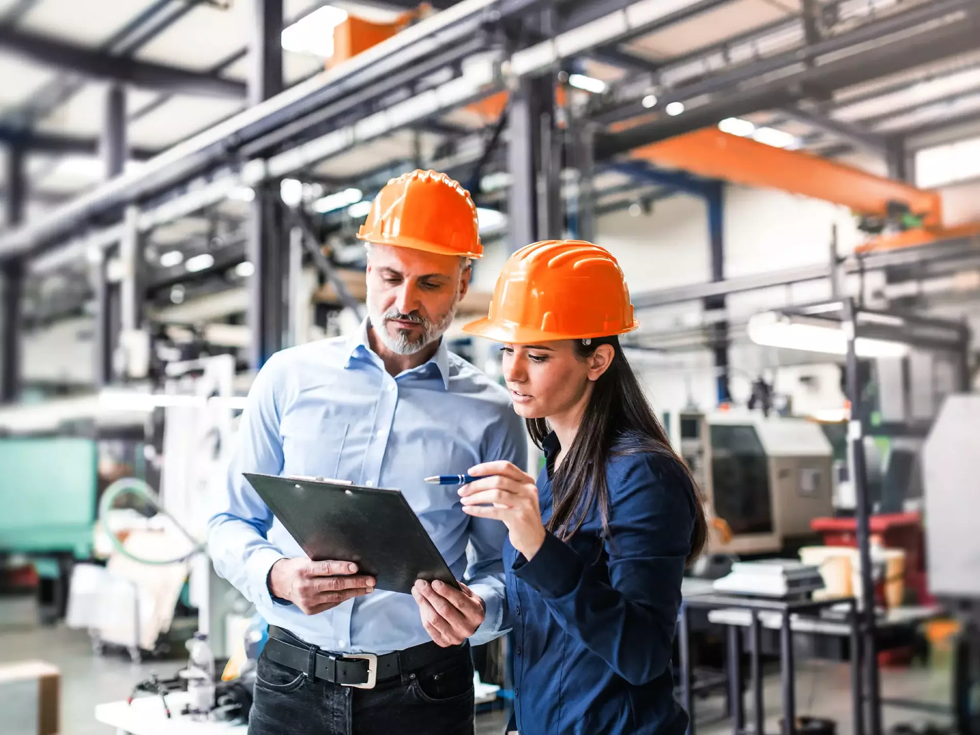 Ein Industrieller und eine Ingenieurin prüfen in einer Fabrik Dokumente