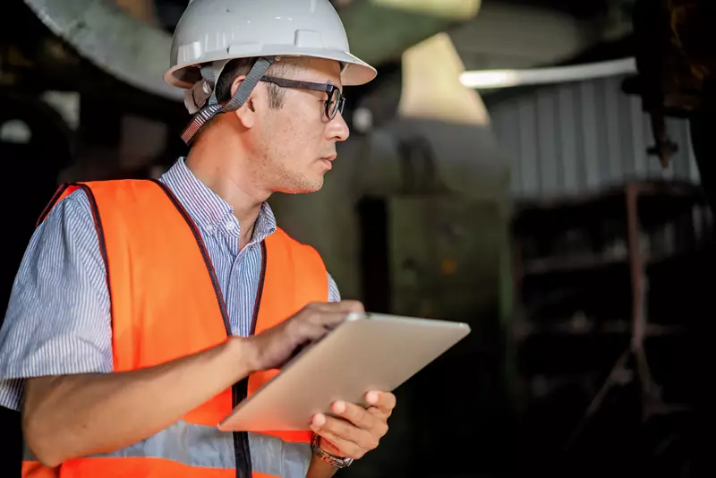 Ein asiatischer Ingenieur arbeitet in einer Fabrik an einem Tablet