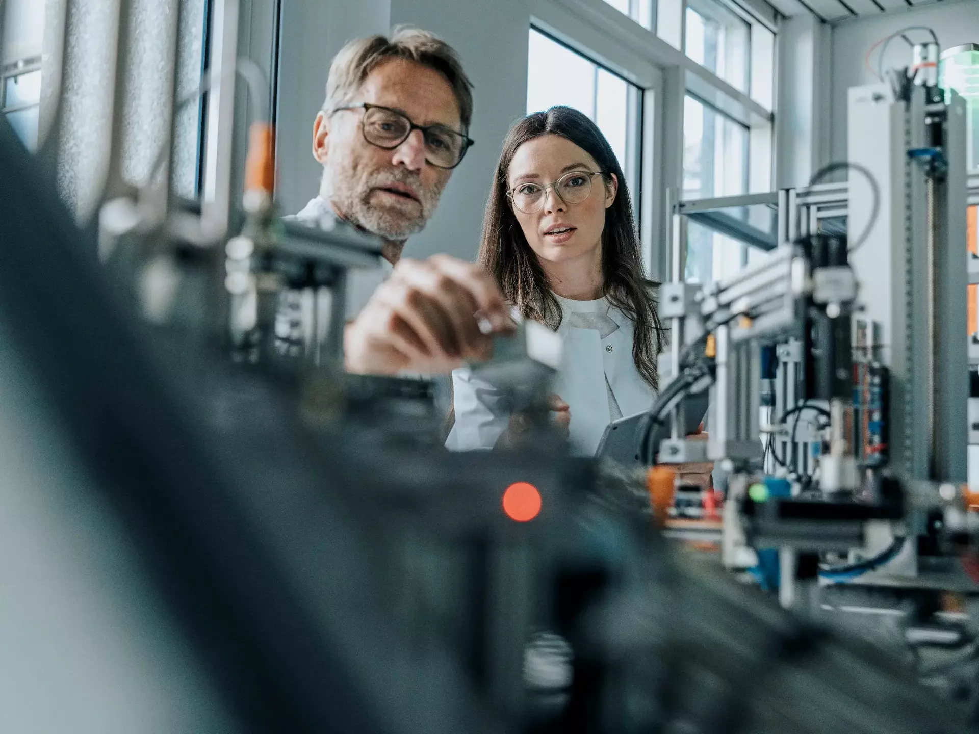 Male scientist with young woman examining machinery in laboratory Male scientist with young woman examining machinery in laboratory