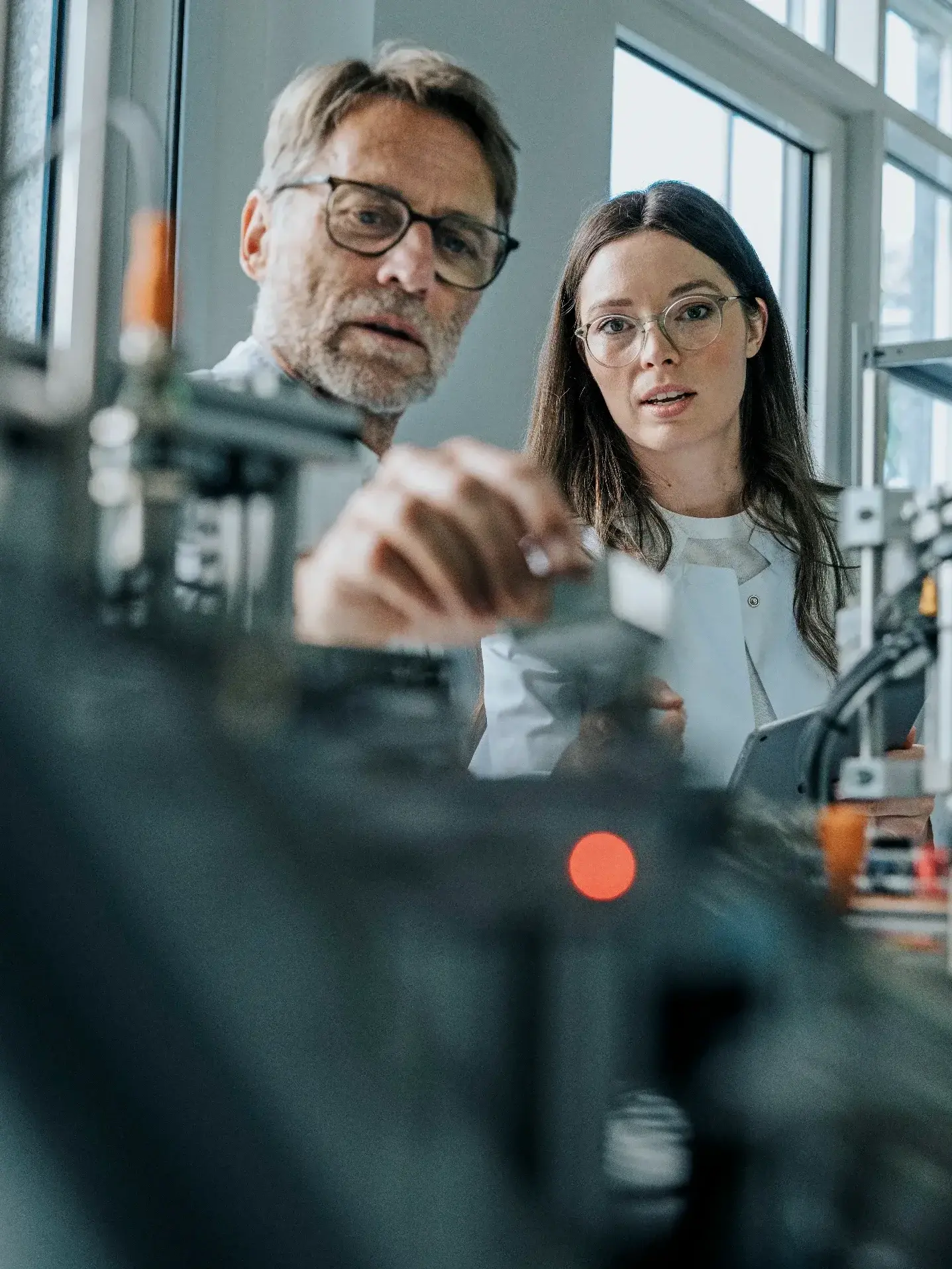 Male scientist with young woman examining machinery in laboratory Male scientist with young woman examining machinery in laboratory