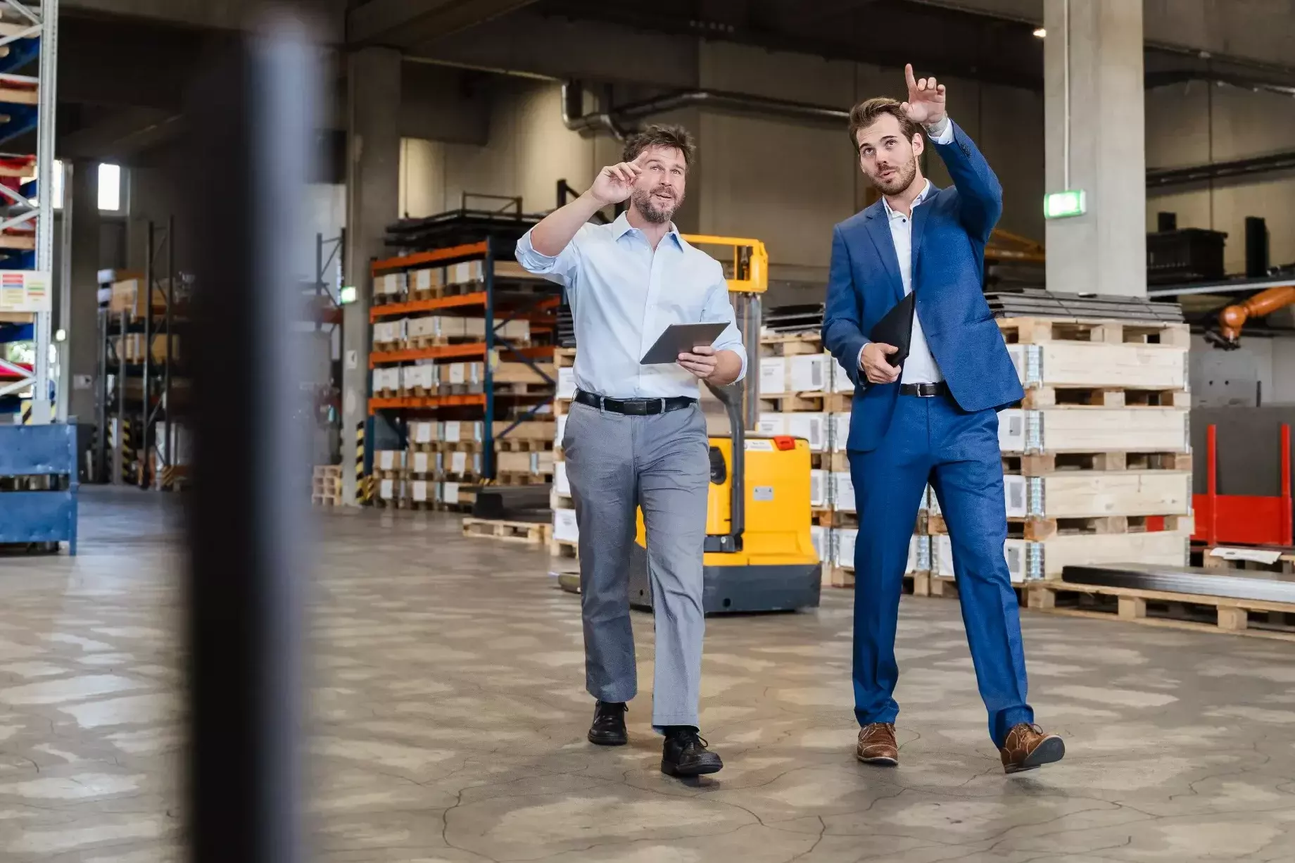 Businessman consulting at warehouse with colleague while walking at factory Businessman consulting at warehouse with colleague while walking at factory