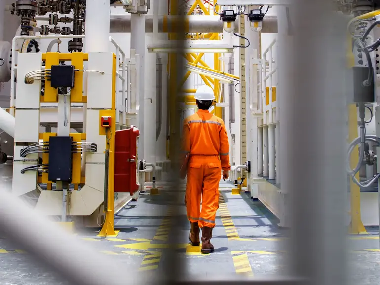 Man with helmet walking through oil rig Man with helmet walking throug oil rig