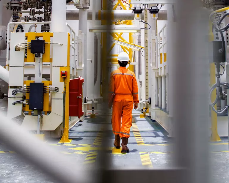 Man with helmet walking throug oil rig