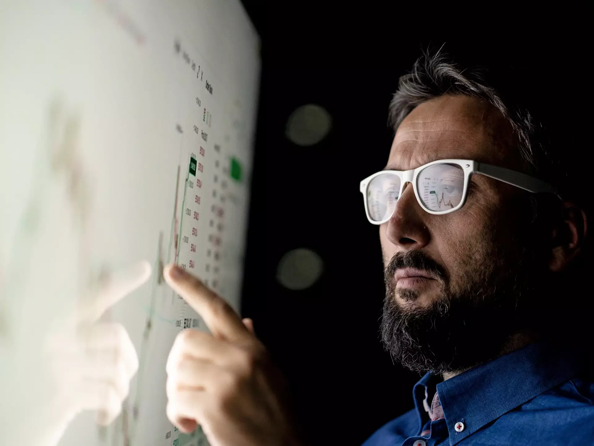 Businessman looking at graph on smart glass panel Businessman looking at graph on smart glass panel