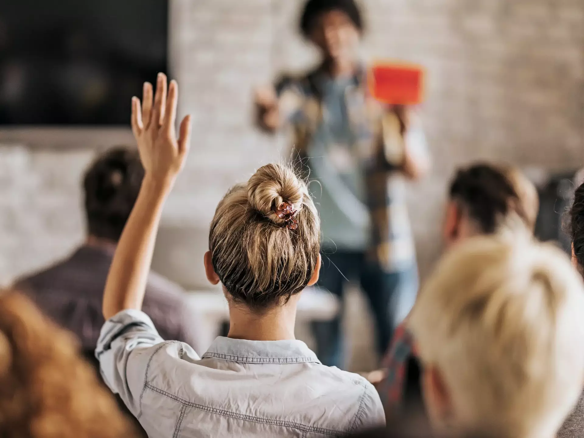 Backview of a woman wants to ask a question on a seminar