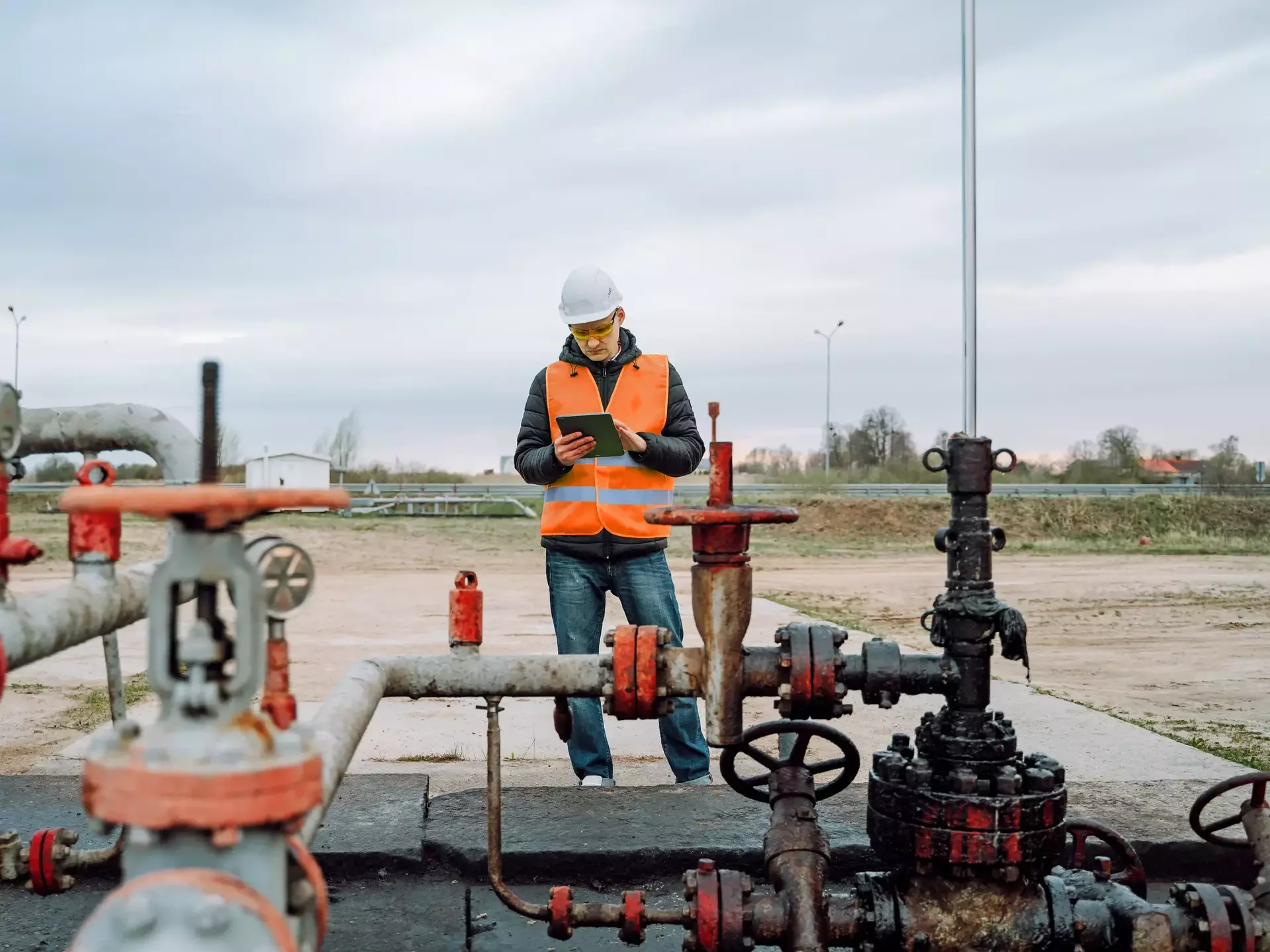 Stationary or technical engineer at work checking valve pipes calculating and analyzing charge of oil and gas in digital tablet