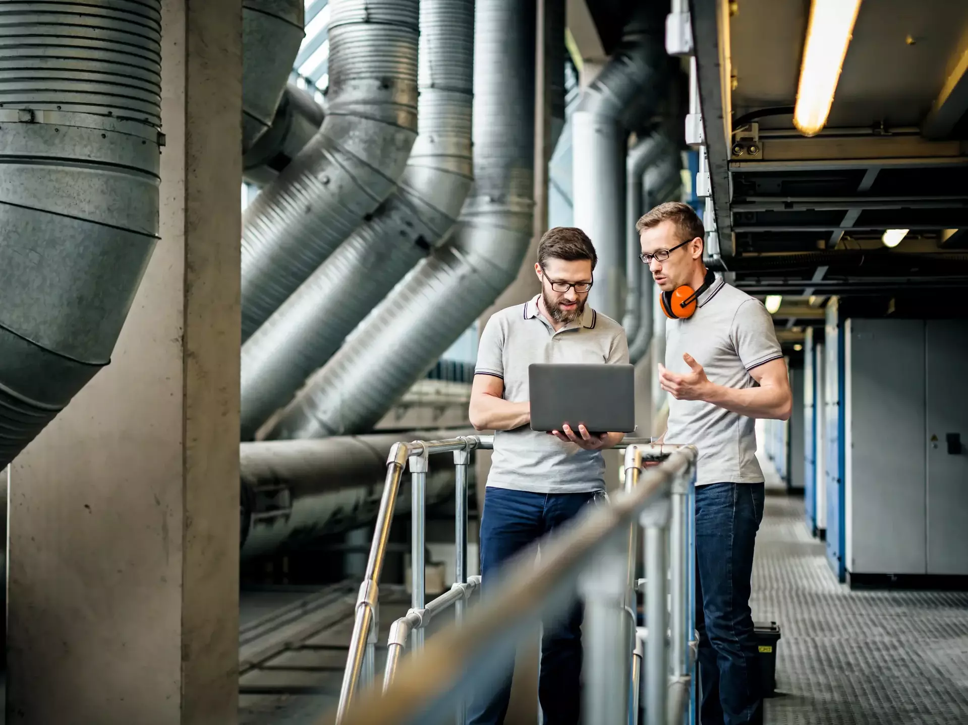 Two engineers with laptop in large printery Two engineers with laptop in large printery